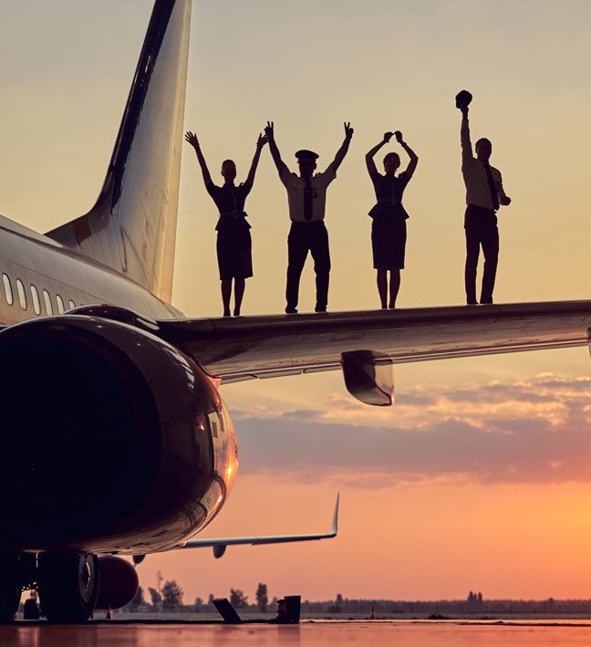 airline team members cheering on top of the wing of a plane